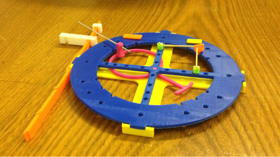 A imagem apresenta o recurso didático denominado Círculo Trigonométrico, que é composto por peças confeccionadas por impressão 3D, com sua respectiva identificação em braille. É composto por circunferência com raio aproximado de 8cm, e furos para encaixes das identificações ângulo, seno, cosseno e tangente