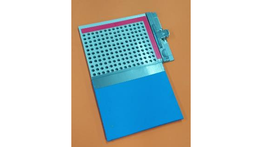 A imagem apresenta o recurso didático denominado Gráfico Tátil, e é composto por peças confeccionadas por impressão 3D, prancheta, EVA, placa metálica, imãs circulares, corrente metálica de bijuterias e fita adesiva. Por baixo da prancheta perfurada tem a placa metálica, e sobre a prancheta é fixado o EVA. Nos eixos da prancheta esta fixado a identificação em braille referente ao espaços para inserção dos imãs e traçagem do gráfico com o uso das correntes.