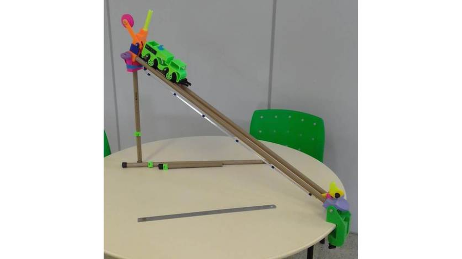 A imagem apresenta o recurso didático denominado Plano Inclinado Tátil, que é composto por tubos de PVC, peças de união e um caminhão, impressos por impressão 3D, para demonstração dos conceitos pedagógicos. O Plano Inclinado Tátil esta montado sobre uma mesa redonda