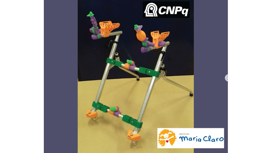 A imagem apresenta uma fotografia de um andador triangular e um logotipo do CNPq e outro do Instituto Maria Claro. Quanto ao andador, ele possui várias peças plásticas nas cores laranja, verde e roxa acopladas a uma estrutura de alumínio. Trata-se de um andador com estrutura lateral em forma triangular com dois rodízios nos apoios frontais e dois apoios de borracha traseiros.